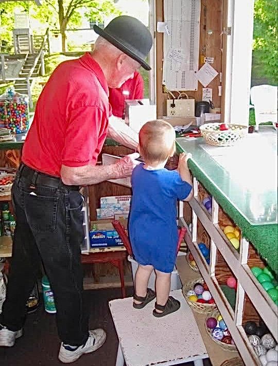 Bob, in his bowler hat, working the shed counter while his grandson Bobby watches from a step stool